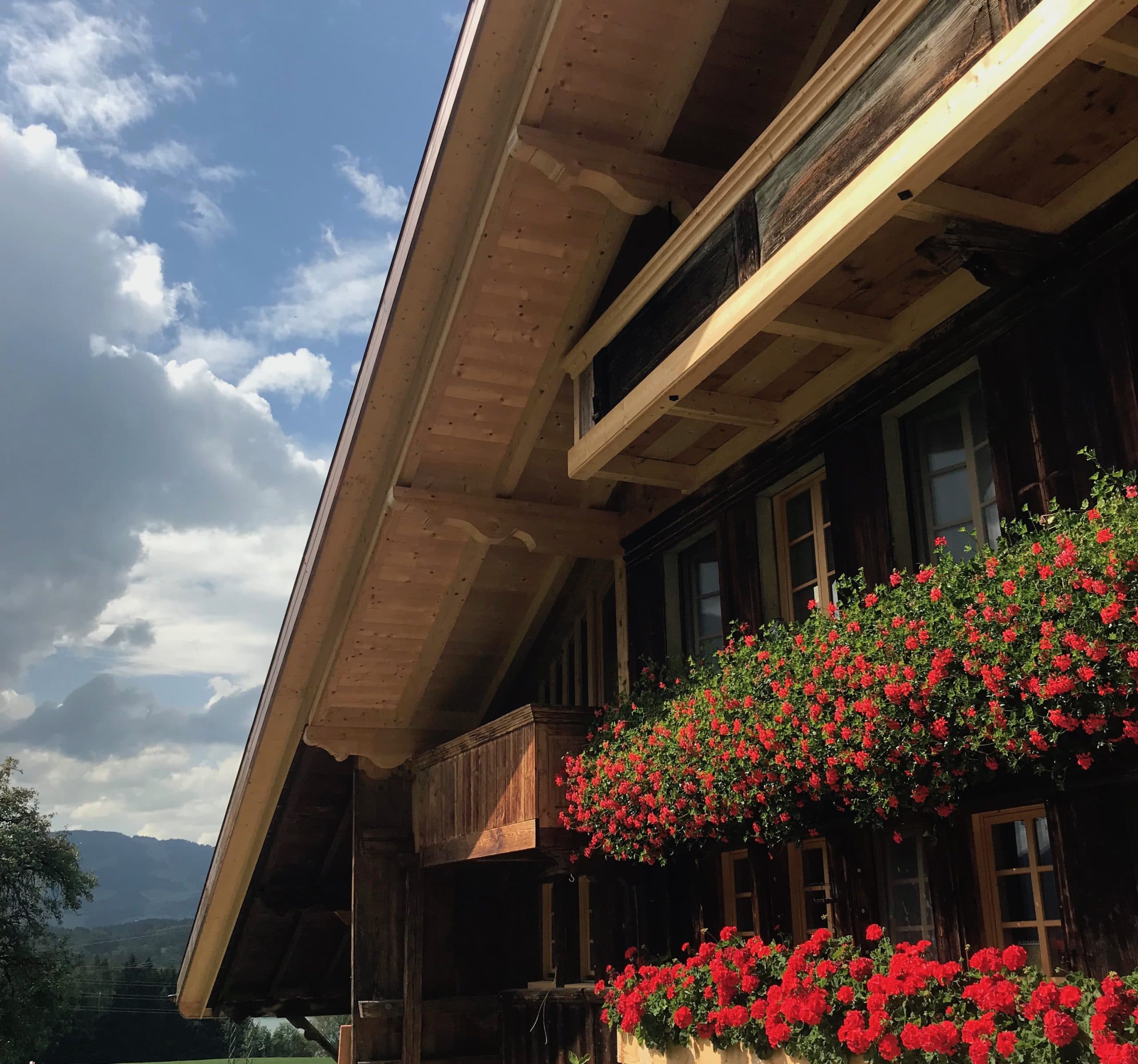 Chalet traditionnel de la Gruyère aux balcons fleuris de géraniums rouges, près de Botterens